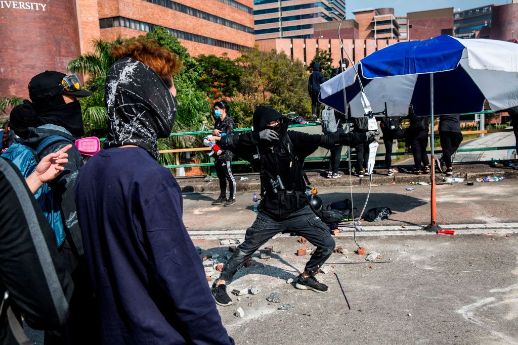A protester unleashes an arrow while standing on a barricaded street outside The Hong Kong Polytechnic University on Nov. 15, 2019. (ISAAC LAWRENCE&mdash;AFP/Getty Images)