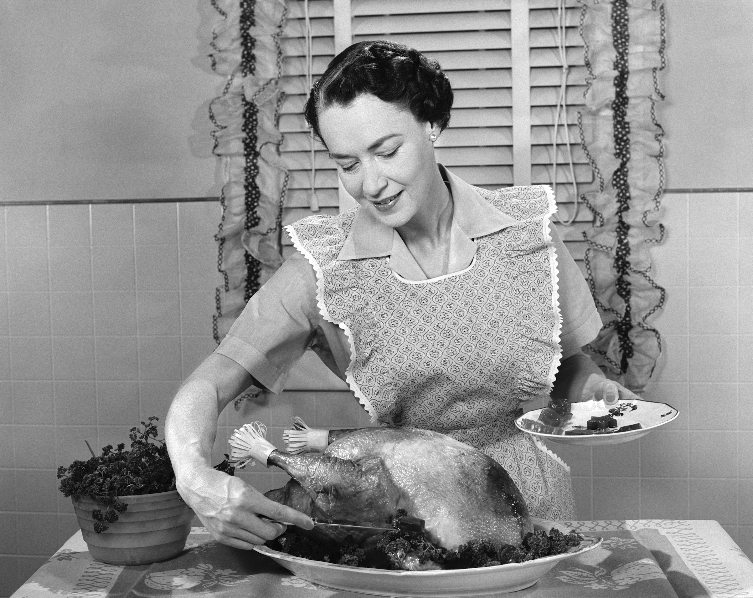 A woman dished cranberry sauce around a turkey in the 1950s (H. Armstrong Roberts/ClassicStock/Getty Images)