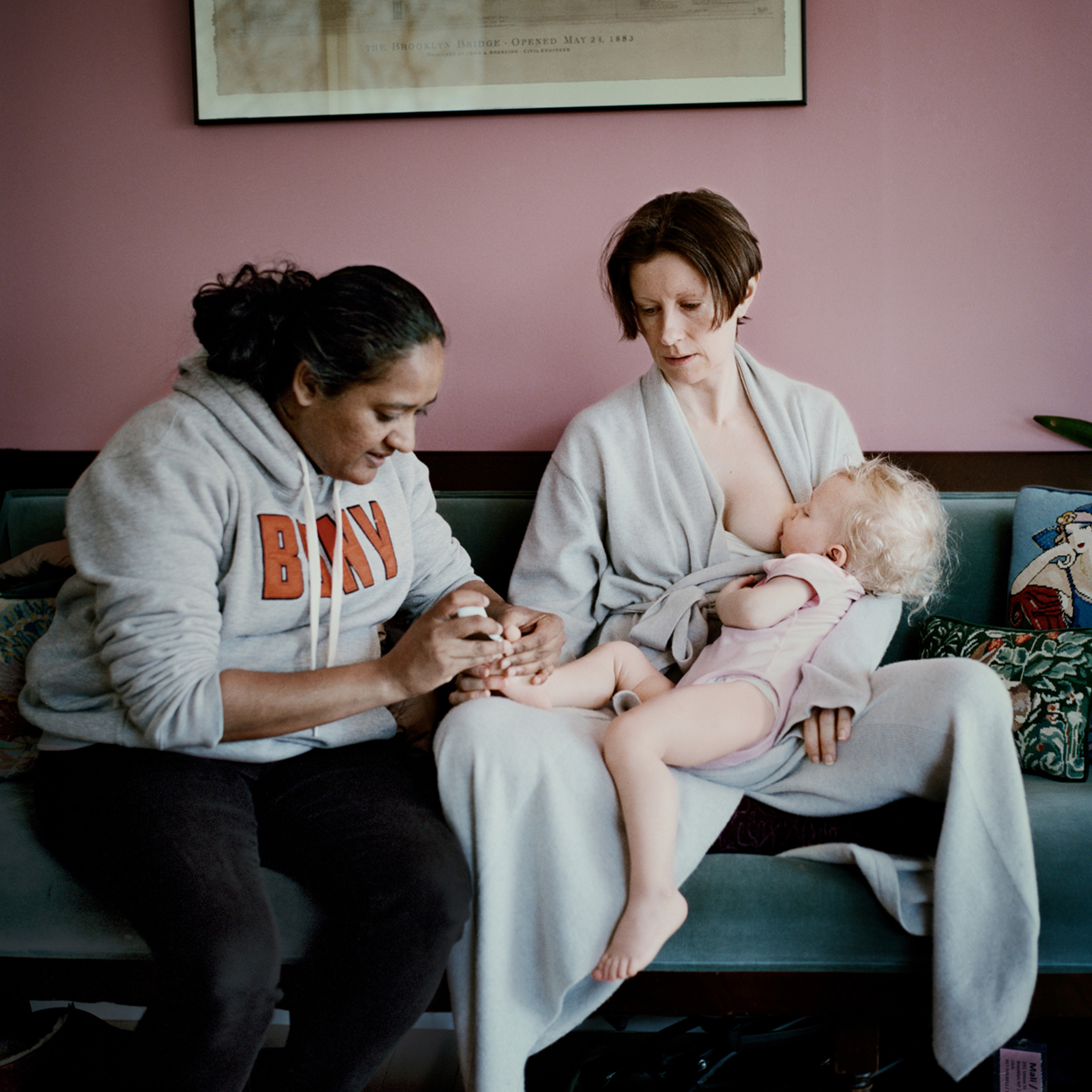 Rachel Kahan nurses her daughter Michaela, while nanny Annie Nabbie trims the child's toenails. "At What Cost?," Oct. 21 issue. (Anastasia Taylor-Lind for TIME)