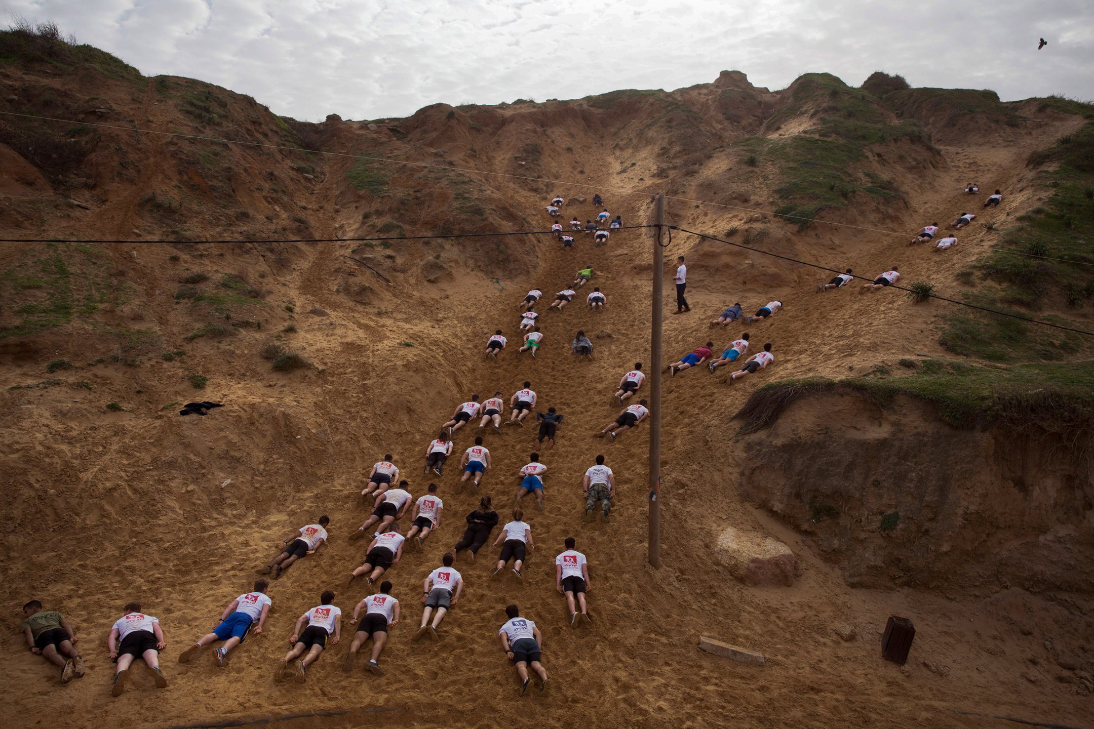 High school seniors preparing to join the Israeli military crawl out in sand dunes during an exercise at a privately run  camp for military combat fitness in Herzliya on Feb. 1.