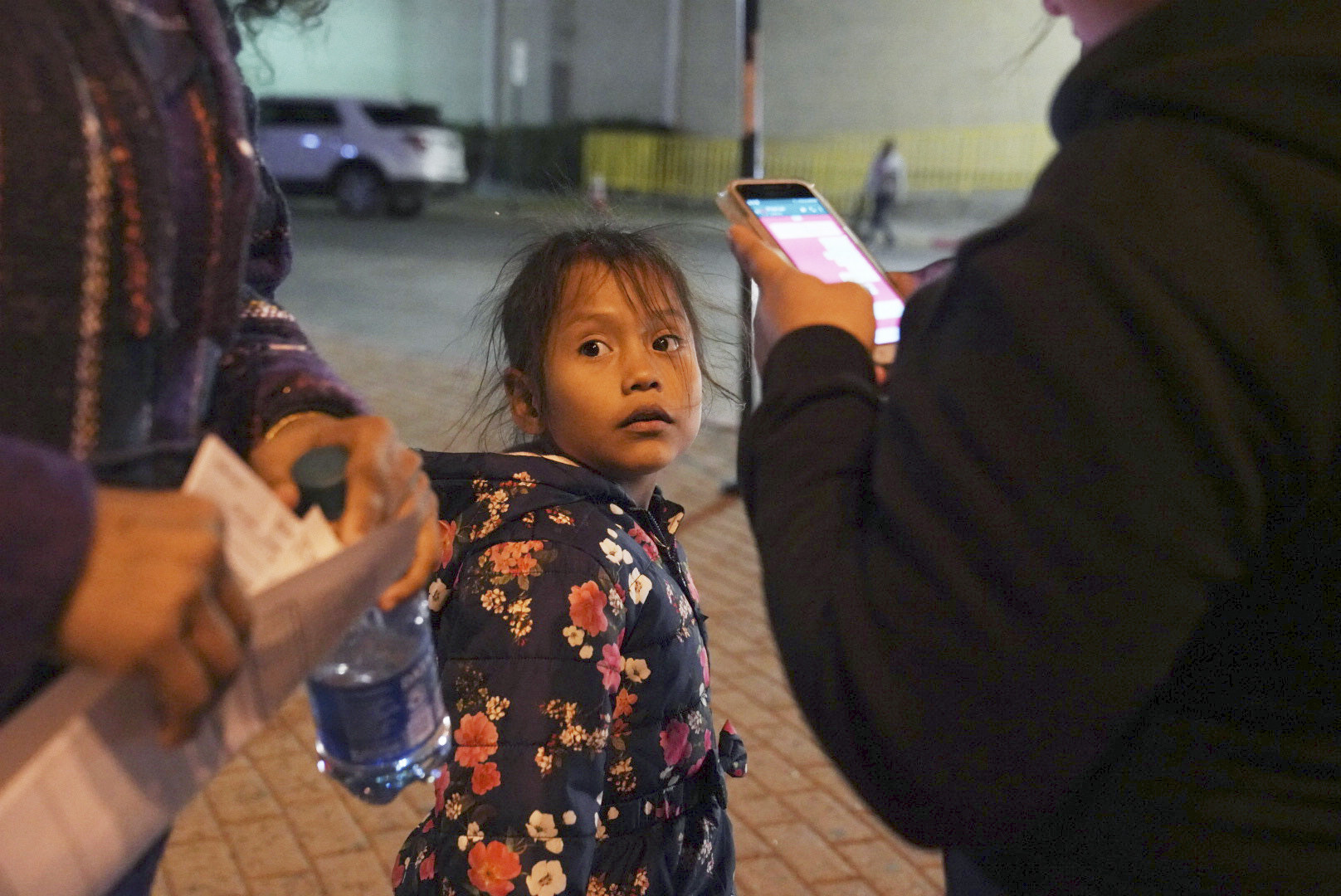 A 7-year-old asylum-seeker waits as her mother Isabel, right, and immigration lawyer Charlene D'Cruz, left, as they figure out where they will be spending the night after being processed at the Port of Entry in Brownsville, Texas, on Dec. 17, 2019. (Veronica G. Cardenas—AP)