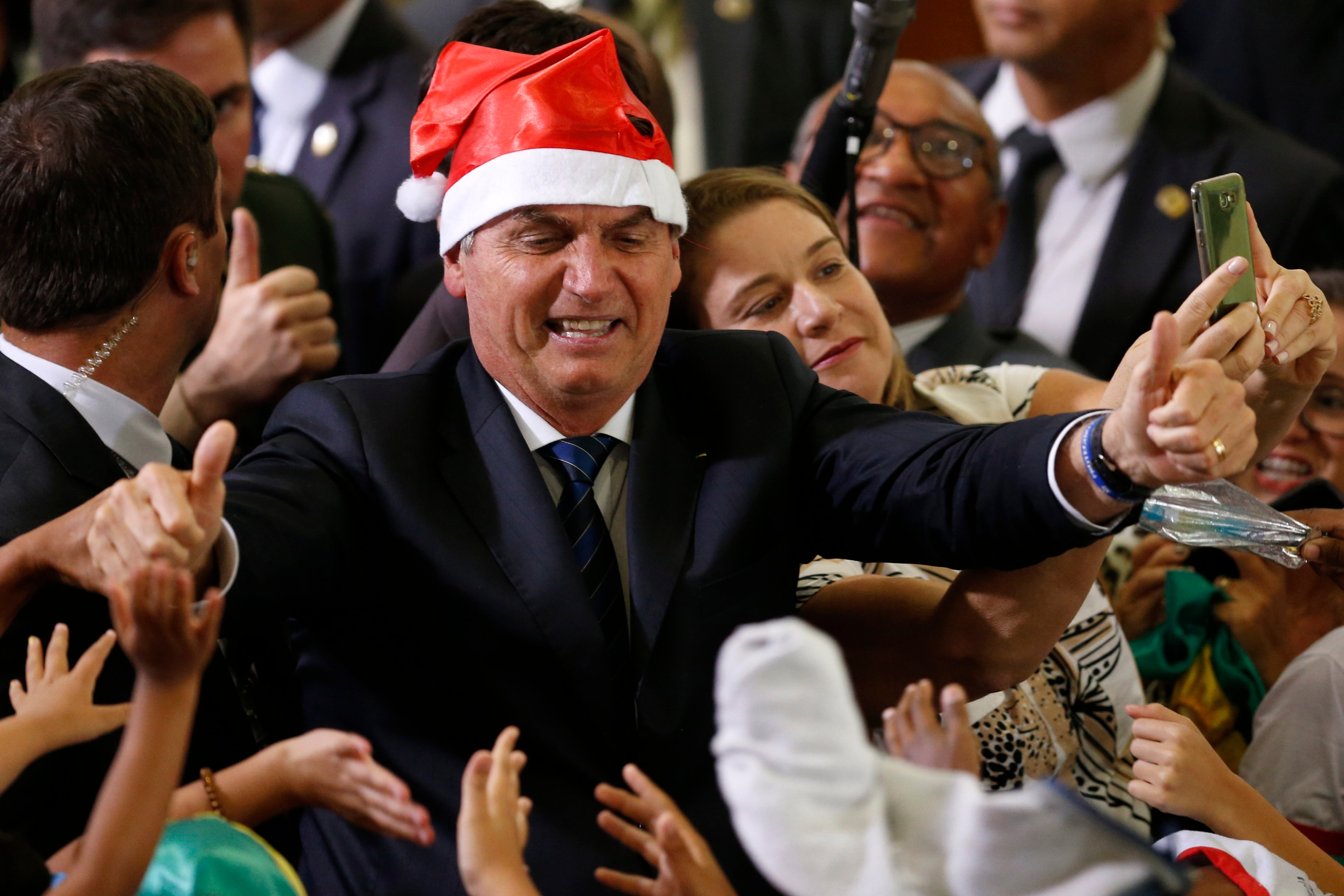 Brazil's President Jair Bolsonaro wears a Santa hat during the Christmas celebration with staff and students at the Planalto Presidential Palace, in Brasilia, Brazil, Thursday, Dec. 19, 2019. He told Brazilian TV that he temporarily lost his memory after a fall Monday night. (Eraldo Peres / AP)