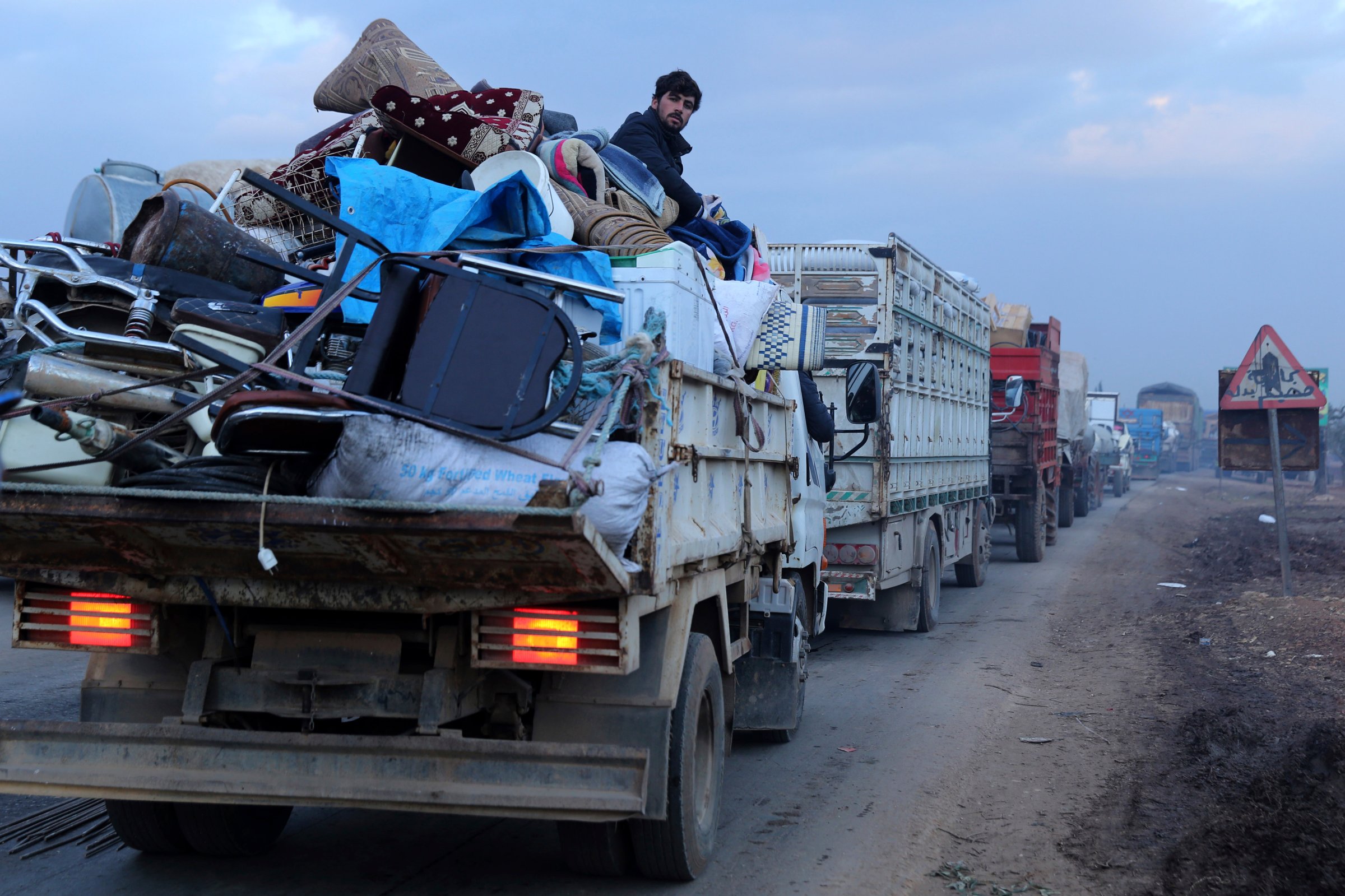 A man rides in a truck as civilians flee