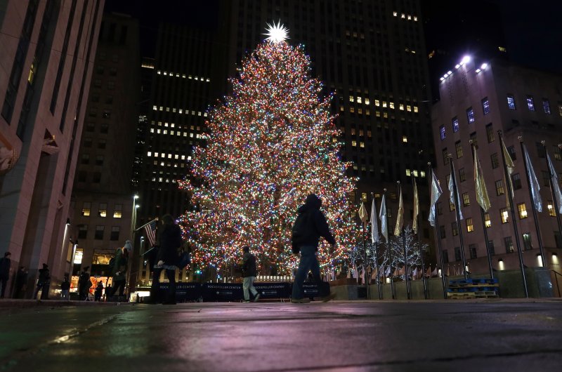 A man walks past the Christmas tree in Rockefeller Center before sunrise on Dec. 5, 2019, in New York City.