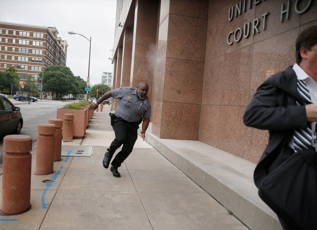 A security guard and a man run for cover as bullets ricochet off the Earle Cabell Federal Building as a shooter (at left, far background) fires towards them in Dallas on June 17.