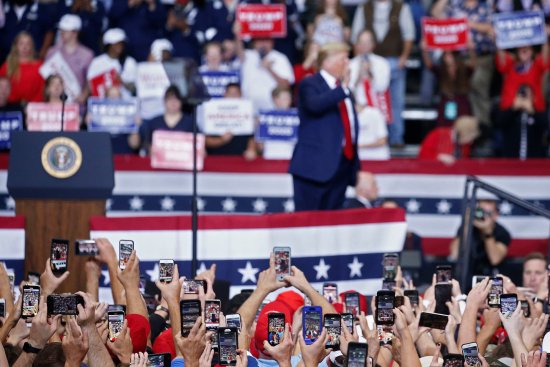 People use their phones to photograph President Donald Trump as he addresses a rally in Monroe, La., on Nov. 6