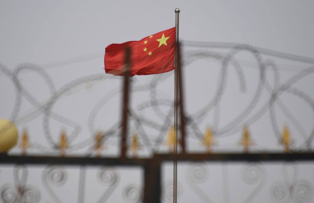 The Chinese flag is seen behind razor wire at a housing compound in Yangisar, south of Kashgar, in China's western Xinjiang region on June 4, 2019. (Greg Baker—AFP/Getty Images)