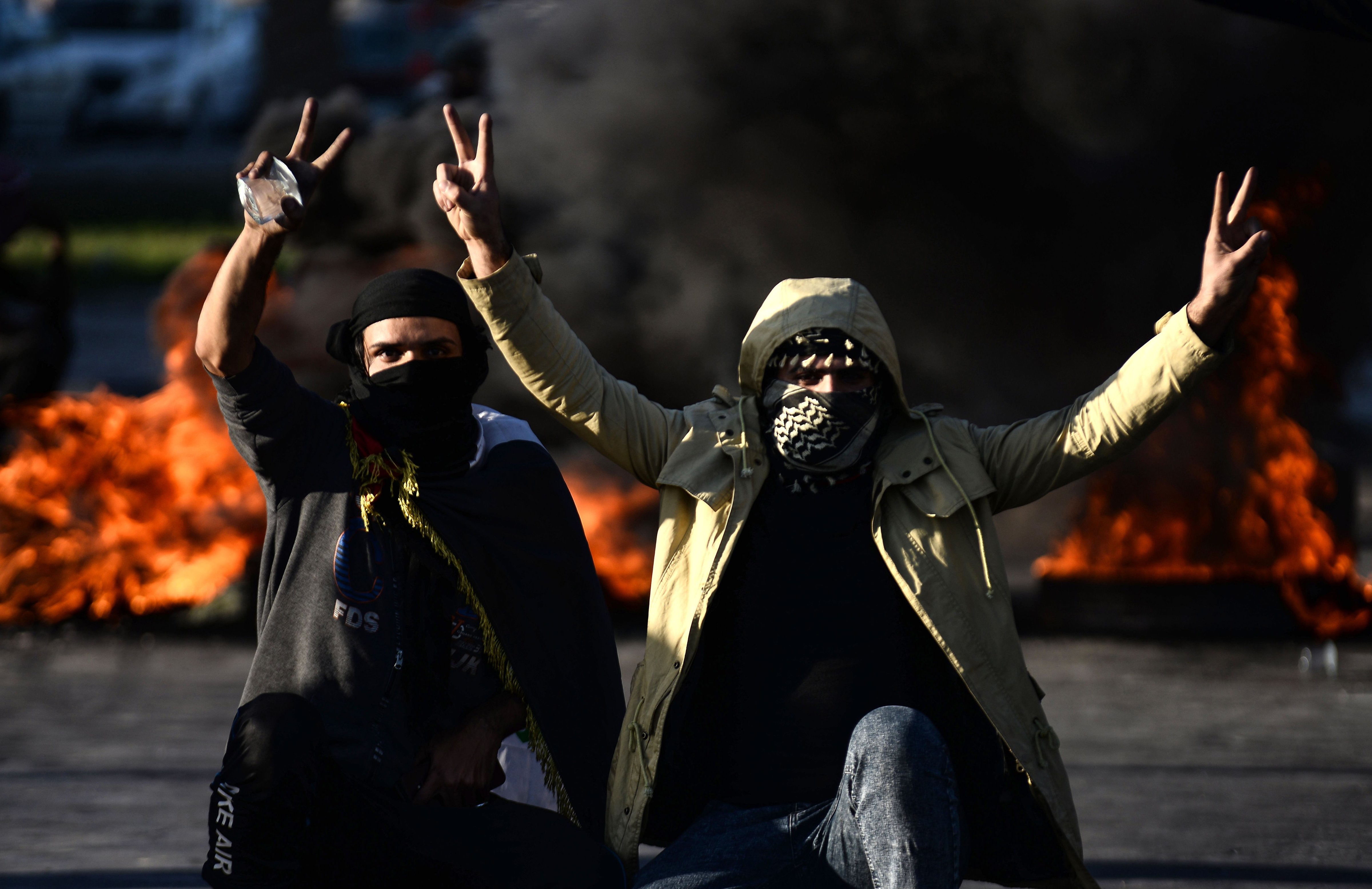 Iraqi demonstrators flash the victory sign next to burning tyres as angry protesters blocked roads in the central shrine city of Najaf, on Jan. 5, 2020 (Haidar Hamdani—AFP via Getty Images)