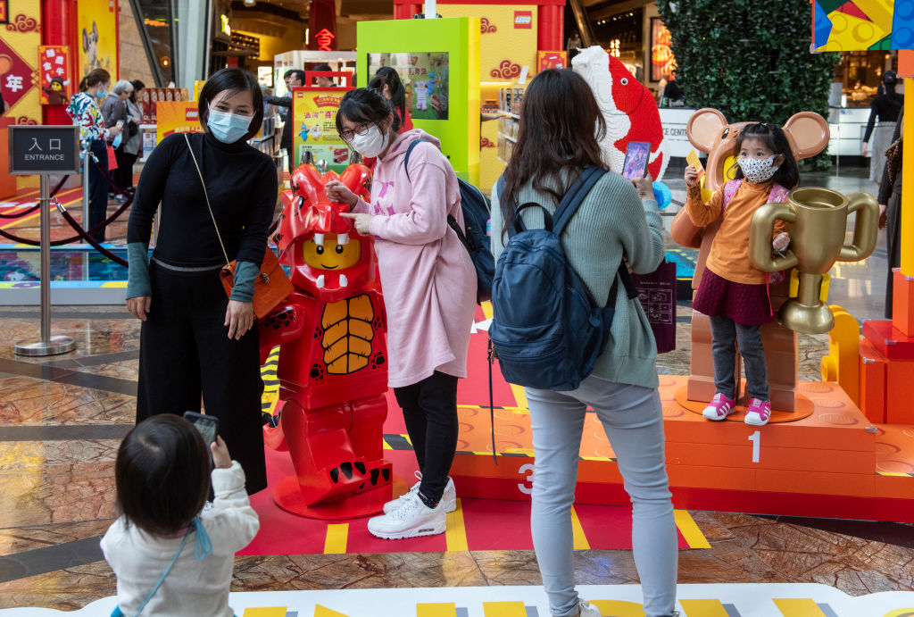 People cover their faces with sanitary masks as they take photos at a shopping mall after the first cases of coronavirus from Wuhan, China were confirmed in Hong Kong. (Miguel Candela–SOPA Images/LightRocket/Getty Images)