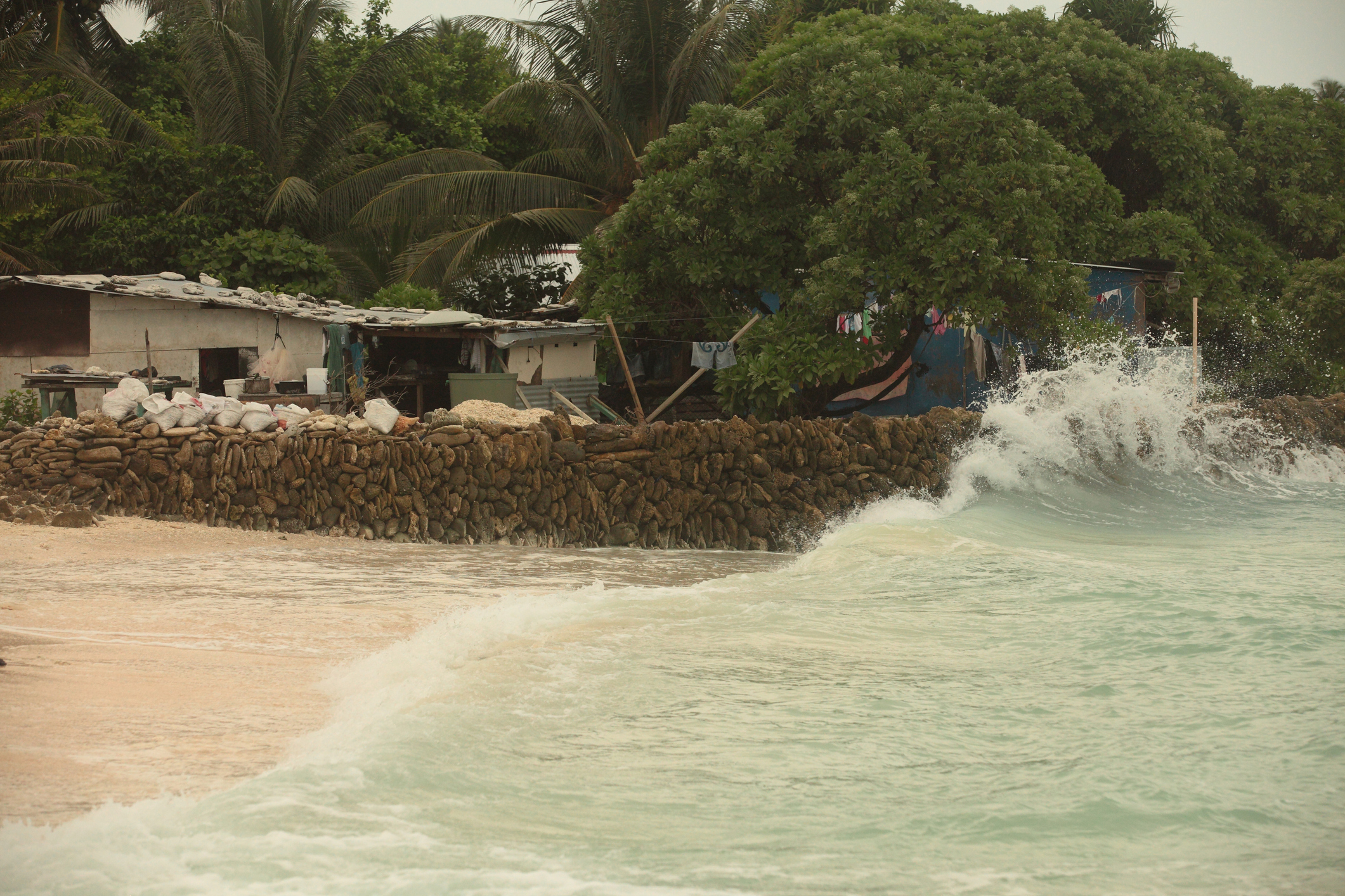 Waves hit a makeshift wall, protecting a coastal house from rising sea levels on Tarawa island, Kiribati. (John Hodjkinson—Getty Images)