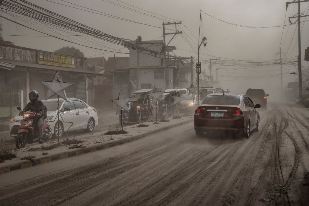 Motorists drive through a road covered in volcanic ash from Taal Volcano's eruption in Lemery, Batangas province, Philippines on Jan. 13, 2020. (Ezra Acayan—Getty Images)