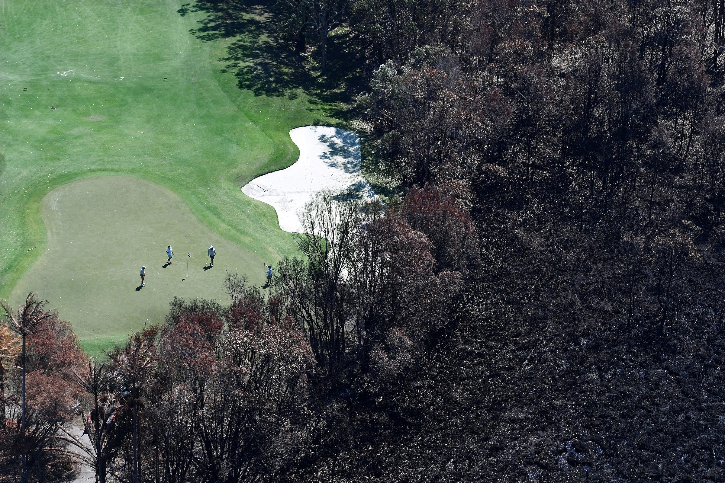 Golfers on the green next to a bushfire-damaged area in Peregian Beach, on the Sunshine Coast, on Sept. 10, 2019. (Dan Peled—EPA-EFE/Shutterstock)