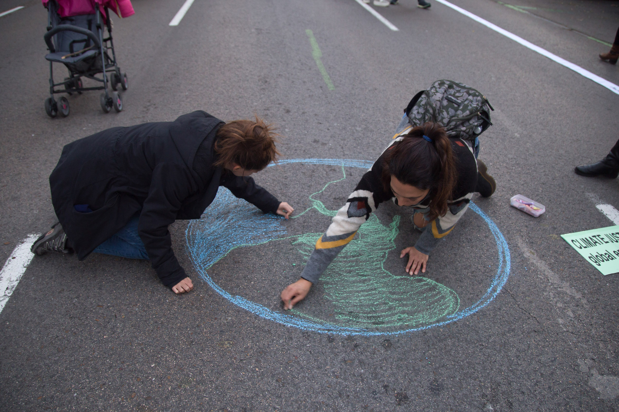 Activists draw the planet earth on the ground during the