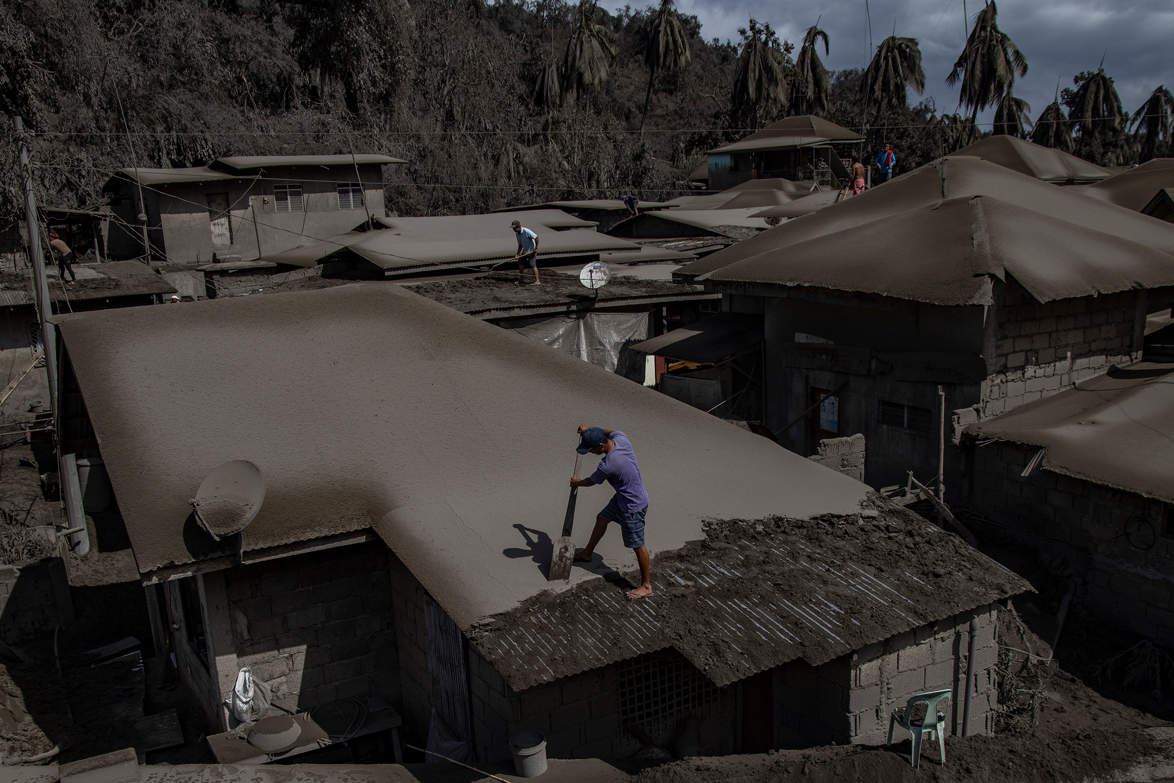 Men clean rooftops of ash from the recent eruption. (Ezra Acayan—Getty Images)