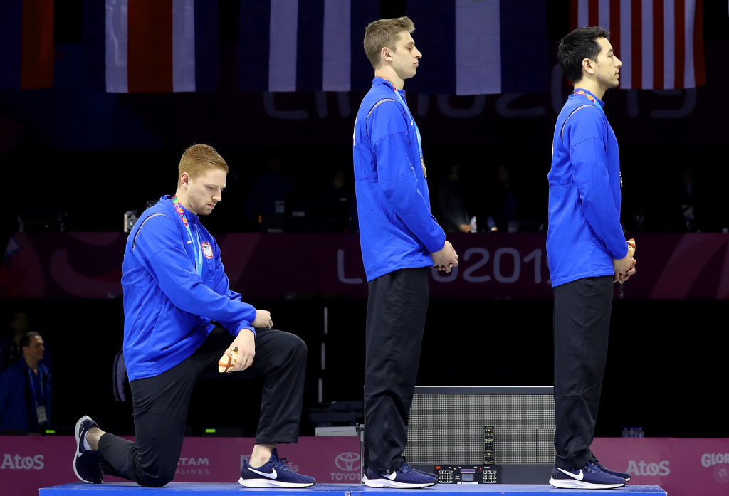 Gold medalist Race Imboden of the United States takes a knee during the National Anthem Ceremony on the podium of Fencing Men's Foil Team Gold Medal Match on Day 14 of Lima 2019 Pan American Games on August 09, 2019 in Lima, Peru. (Leonardo Fernandez/Getty Images)