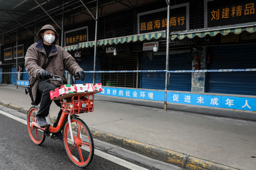 A man wears a mask while riding a bike past the closed Huanan Seafood Wholesale Market, which has been linked to the coronavirus in Wuhan, Hubei province, China on Jan. 17, 2020. (Getty Images)