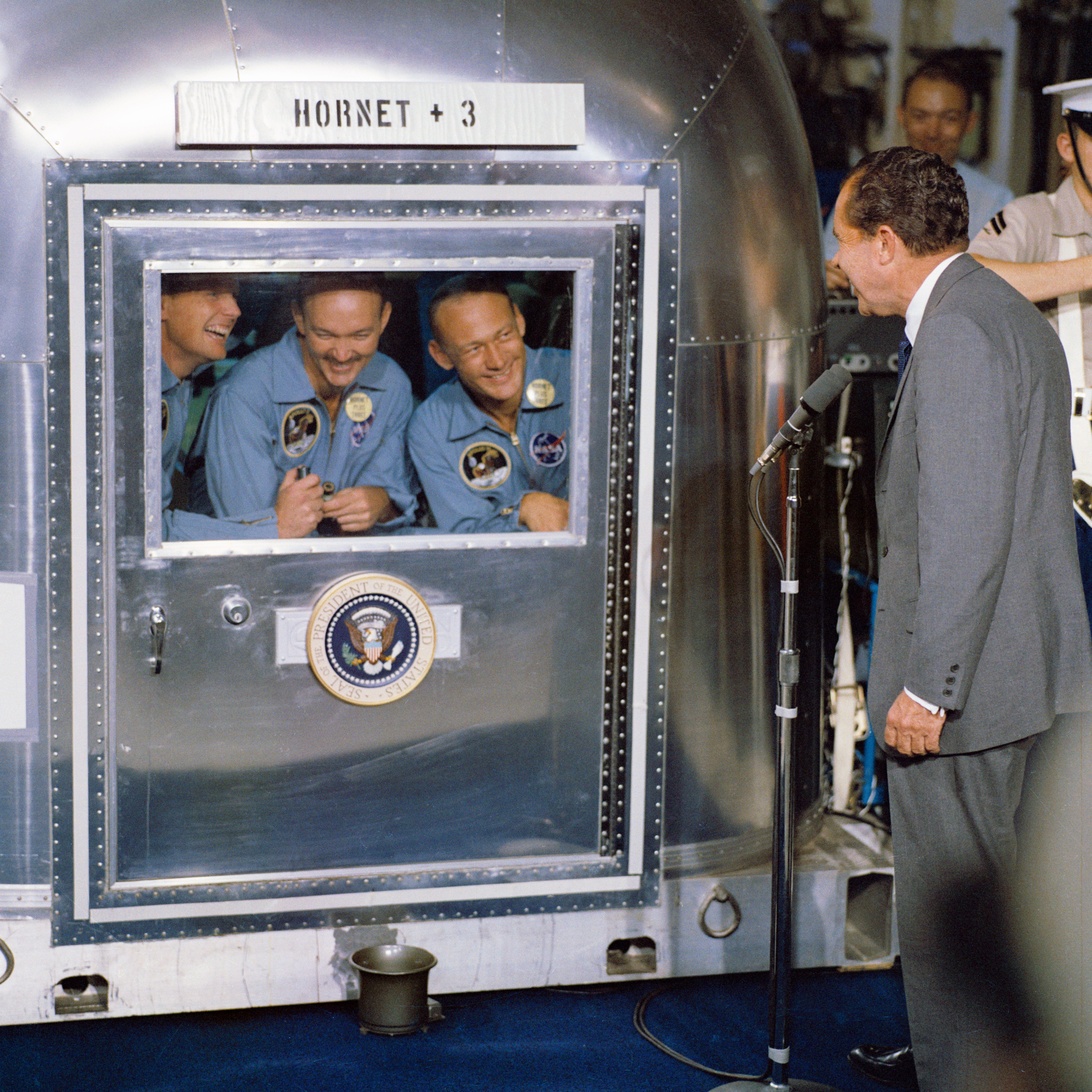 President Nixon talking to the Apollo 11 crew members (left to right: Neil A. Armstrong, Michael Collins, and Buzz  Aldrin Jr.) while the astronauts were in quarantine after returning to Earth from their trip to the moon. (NASA)
