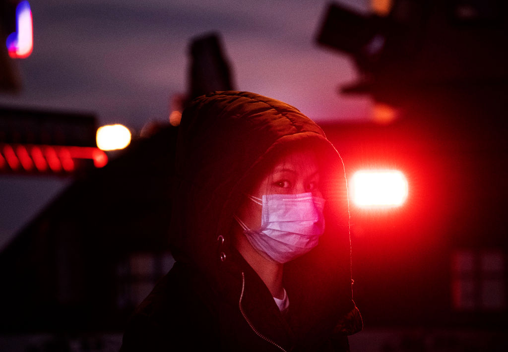 A Chinese woman wears a mask as she stands near the light of a police vehicle on regular duty at Beijing Railway station before the annual Spring Festival on January 21, 2020 in Beijing, China. (Kevin Frayer—Getty Images)
