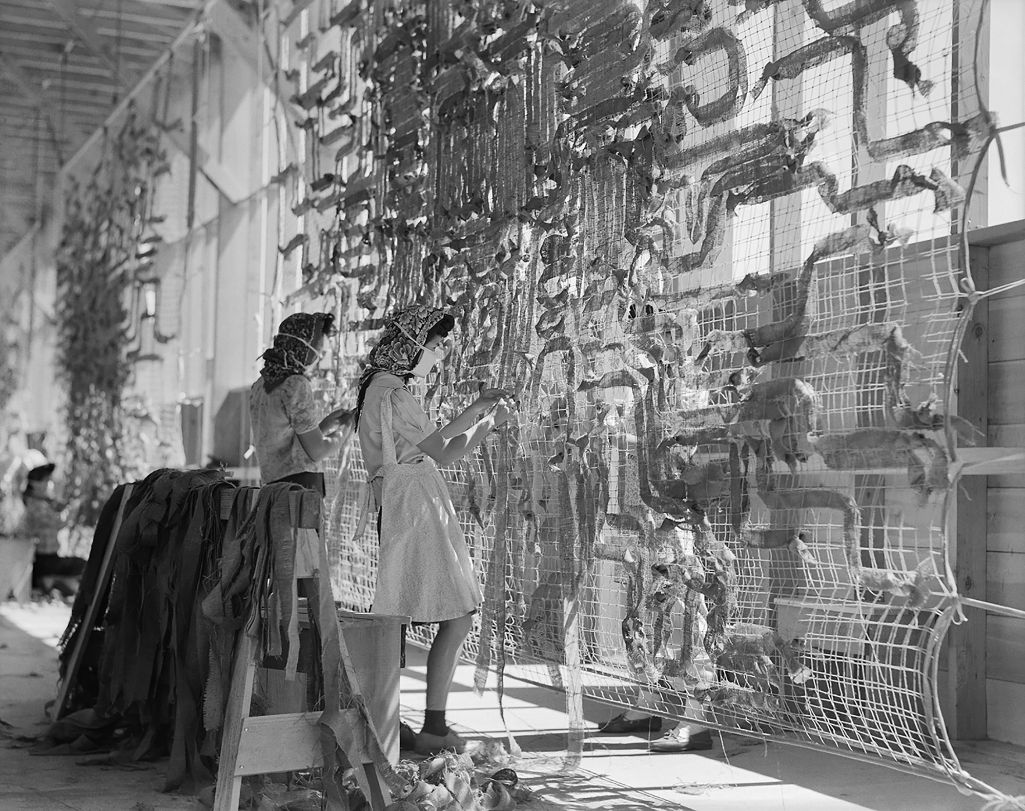 Manzanar Relocation Center, Manzanar, Calif. Making camouflage nets for the War Department. In 1942, Lange was commissioned to photograph the U.S. Government's imprisonment of Japanese Americans. Her negatives were impounded by the Army; she did not see them until 1964. (Dorothea Lange—National Archives/courtesy of MACK)