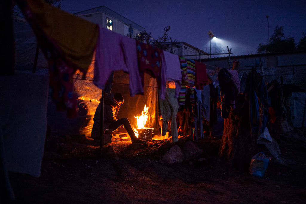 A migrant tries to warm himself in a temporary camp next to the camp in Moria by a small fire on January 22, 2020. (Angelos Tzortzinis–Getty)
