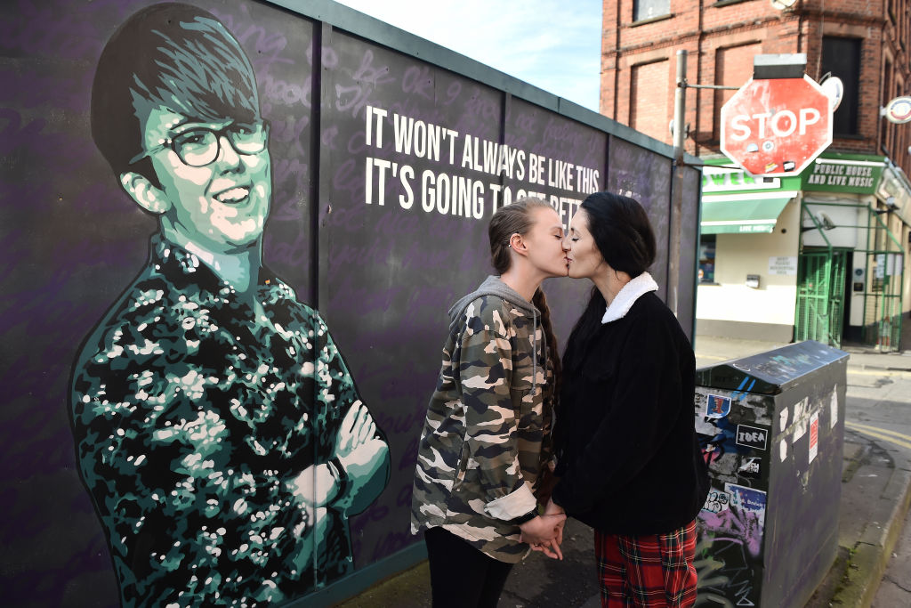 Robyn Peoples (L) and Sharni Edwards, Northern Ireland's first same-sex couple to be legally married, kiss as they pose in front of the Lyra McKee mural during a photo call on February 5, 2020 in Belfast, Northern Ireland. The couple held a pre-wedding press conference ahead of their wedding on Tuesday the 11th of February in the province. Same sex marriages can legally take place for the first time in Northern Ireland from next week following the law change last year. Journalist Lyra McKee was in a same-sex relationship and planned to marry her partner Sara Canning before she was murdered whilst covering a dissident republican riot in Derry last year. (Charles McQuillan—Getty Images)