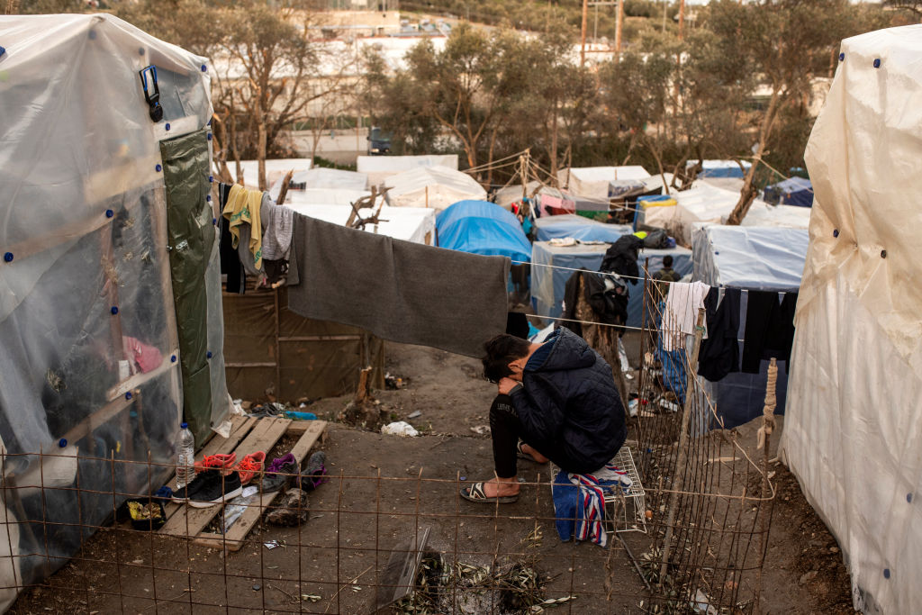 A young migrant bent over himself in front of his tent in the Moria refugee camp on February 2, 2020 in Moria, Greece. (Ivan Romano—Getty Images)