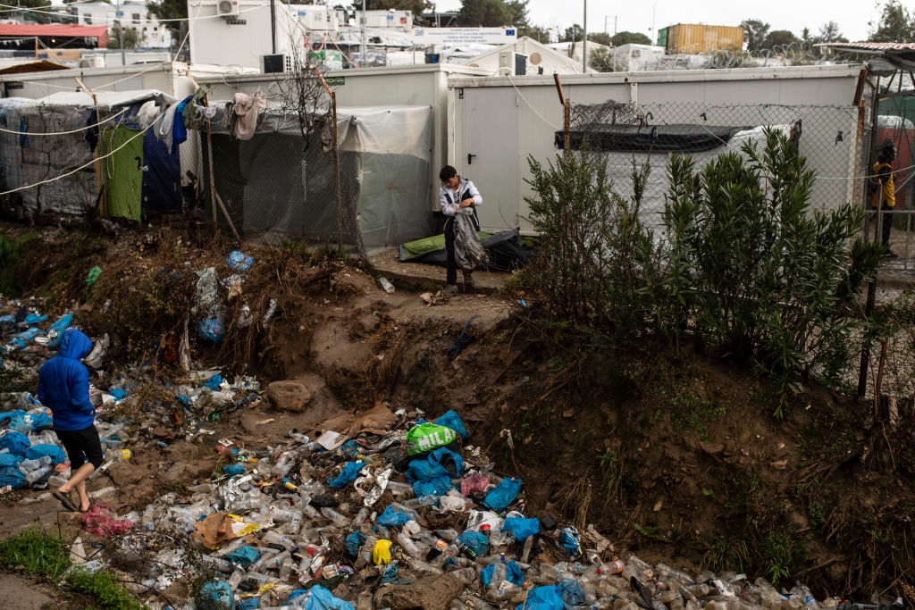 Migrants stand near an accumulation of garbage in the stream of the Moria refugee camp on February 5, 2020 in Moria, Greece. (Ivan Romano—Getty)