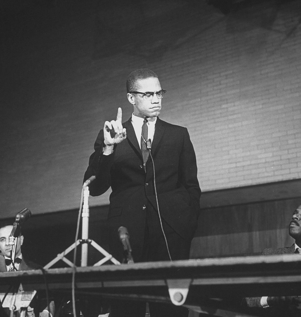 Malcolm X during a speech at a rally as others look on. It's been 55 years since Malcolm X was assassinated while speaking at the Audubon Ballroom in Harlem, New York on Feb. 21, 1965. (The LIFE Picture Collection via Getty Images)