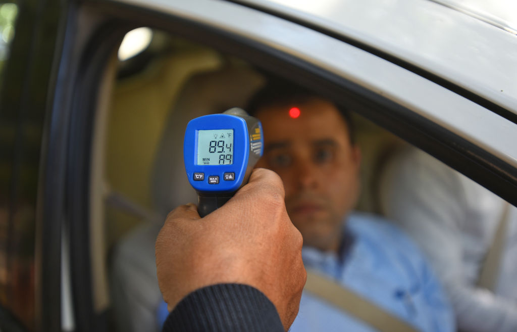 A security guard holds up an infrared thermometer to screen passengers in a car, as a precautionary measure against coronavirus (COVID-19), at Barakhamba Road on March 9, 2020 in New Delhi, India. (Photo by Amal KS/Hindustan Times)