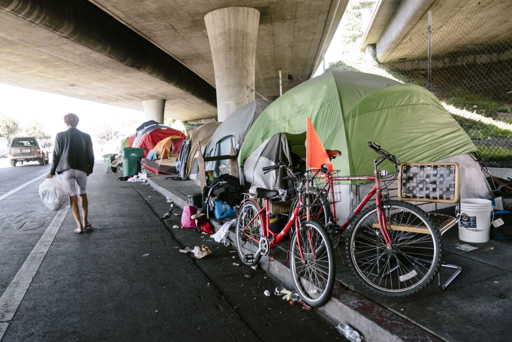 A person walks past a homeless encampment in Oakland, California, on Friday, Aug. 30, 2019.