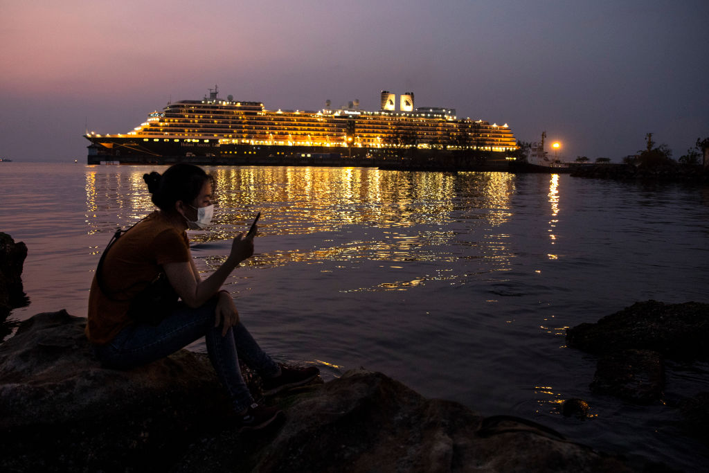 A Chinese woman looks at her mobile sitting near the MS Westerdam cruise ship docked nearby in Sihanoukville, Cambodia on Feb. 17, 2020. (Photo by Paula Bronstein/Getty Images)