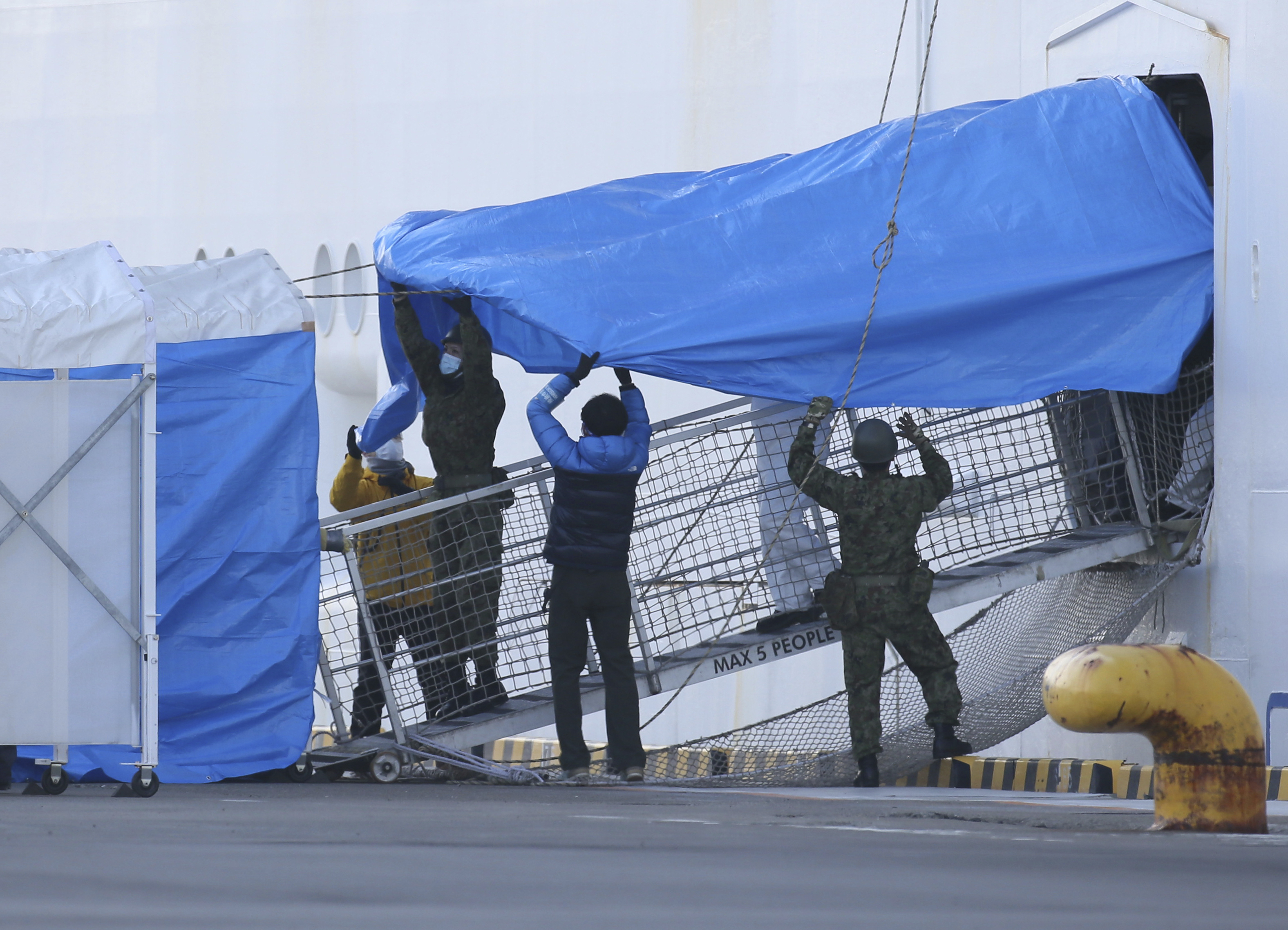 Workers use tarpaulin to cover a gangway off the Diamond Princess cruise at Daikoku Pier in Yokohama, Japan, on Feb. 10, 2020. (Keita Iijima—AP)