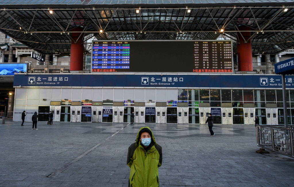 A Chinese man wears a protective mask as he stands outside a main entrance at Beijing West Railway Station as it is nearly empty on February 16, 2020 in Beijing, China. (Kevin Frayer–Getty Images)