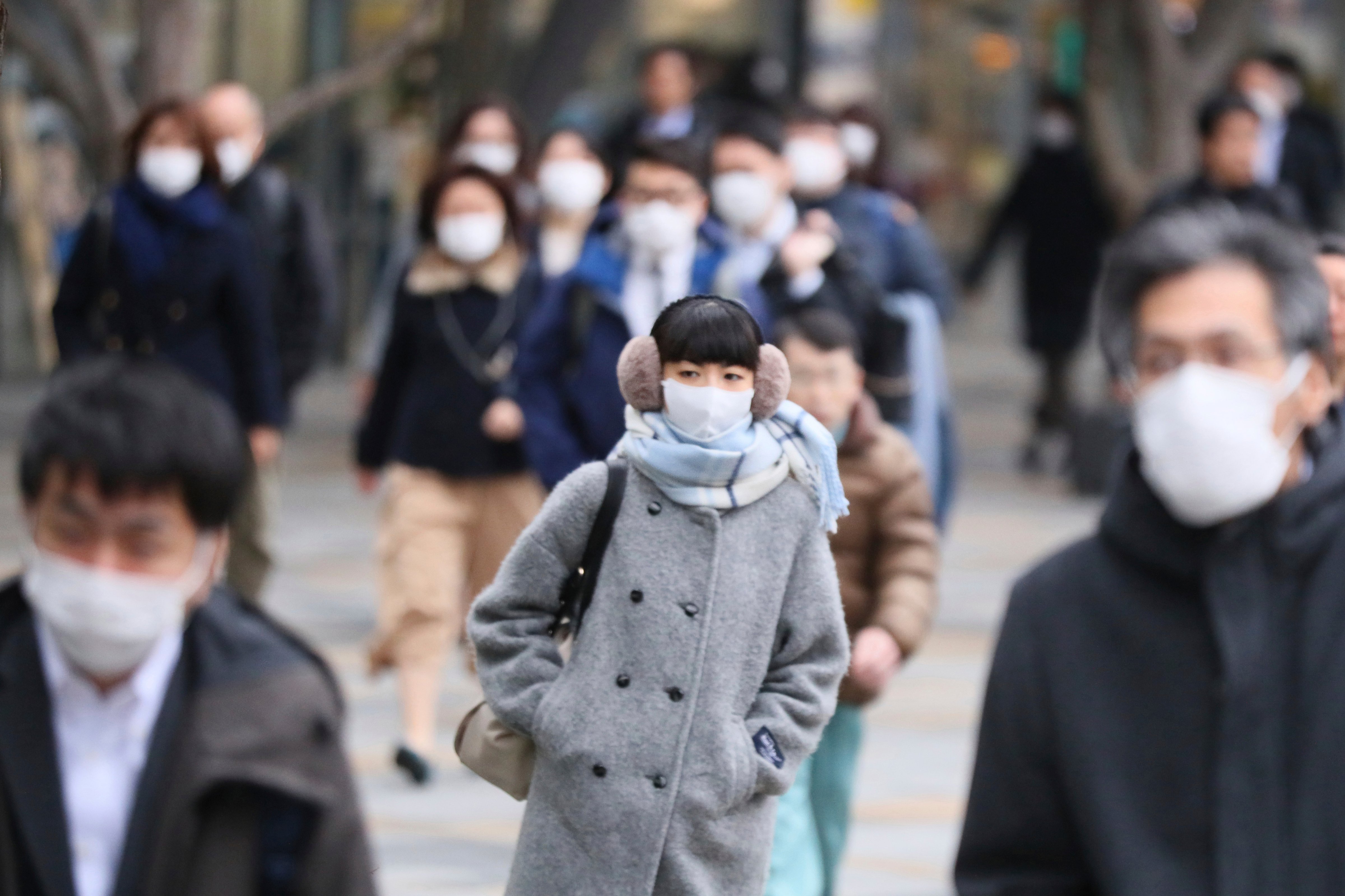 People wearing mask head for their offices and others in Tokyo on Feb. 26, 2020. (The Yomiuri Shimbun/AP)