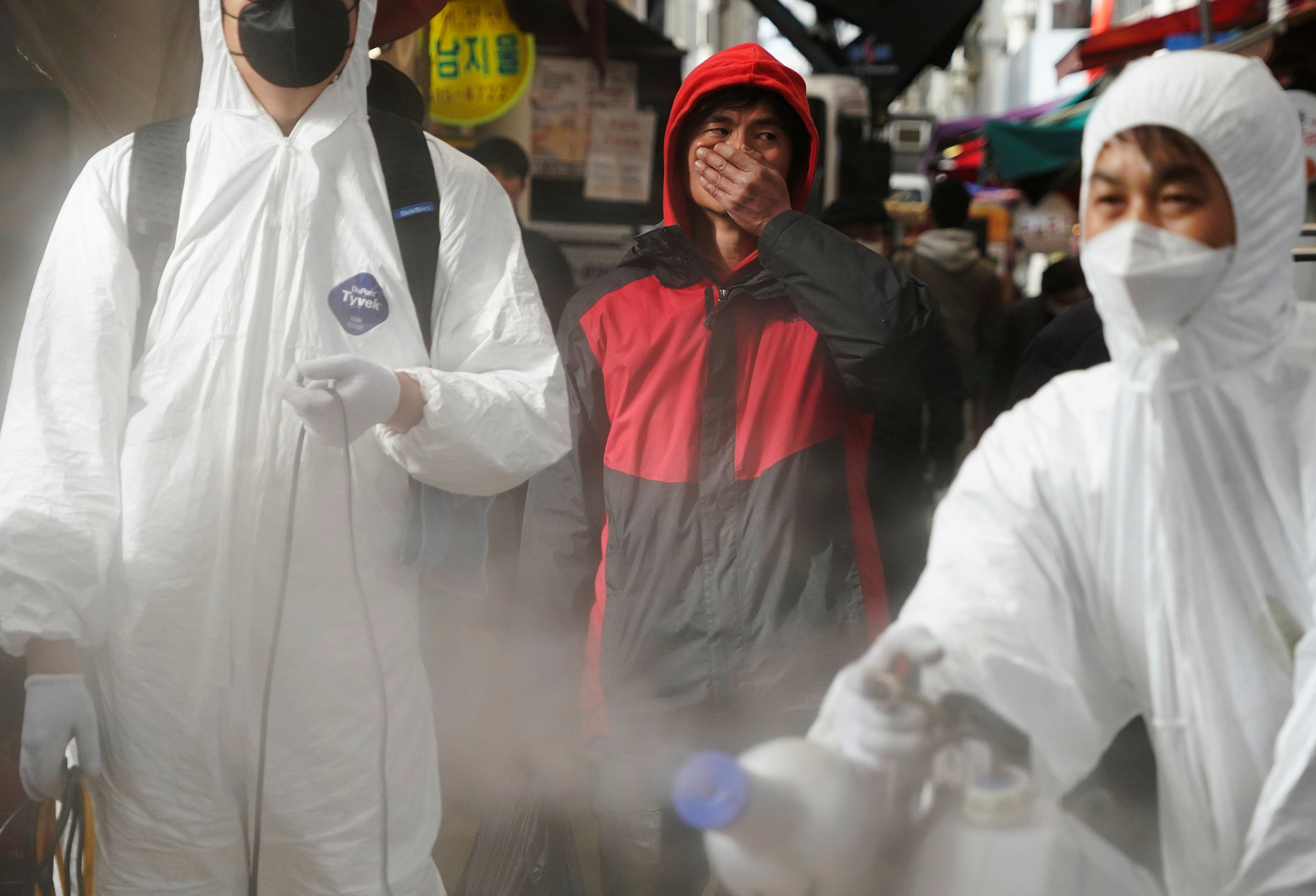 A man reacts as employees from a disinfection service company sanitize a traditional market in Seoul on Feb. 26 (Hong-Ji Kim—REUTERS)