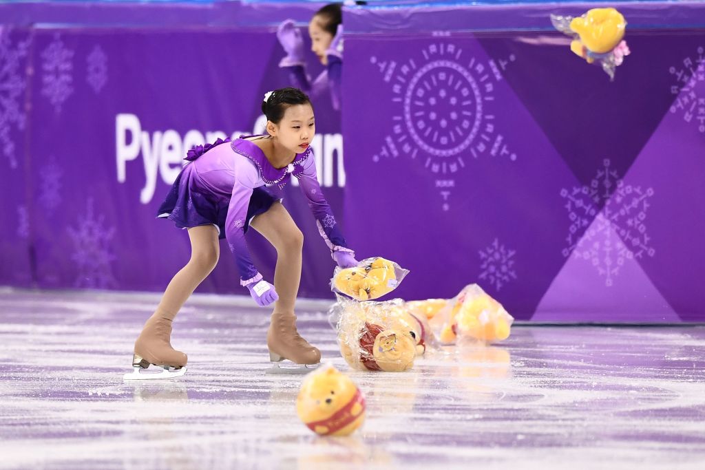 Flower girls collect Winnie the Pooh teddy bears thrown by supporters of Japan's Yuzuru Hanyu before he competed in the men's single skating short program of the figure skating event during the Pyeongchang 2018 Winter Olympic Games at the Gangneung Ice Arena in Gangneung on February 16, 2018. (Getty Images—Aris Messinis)
