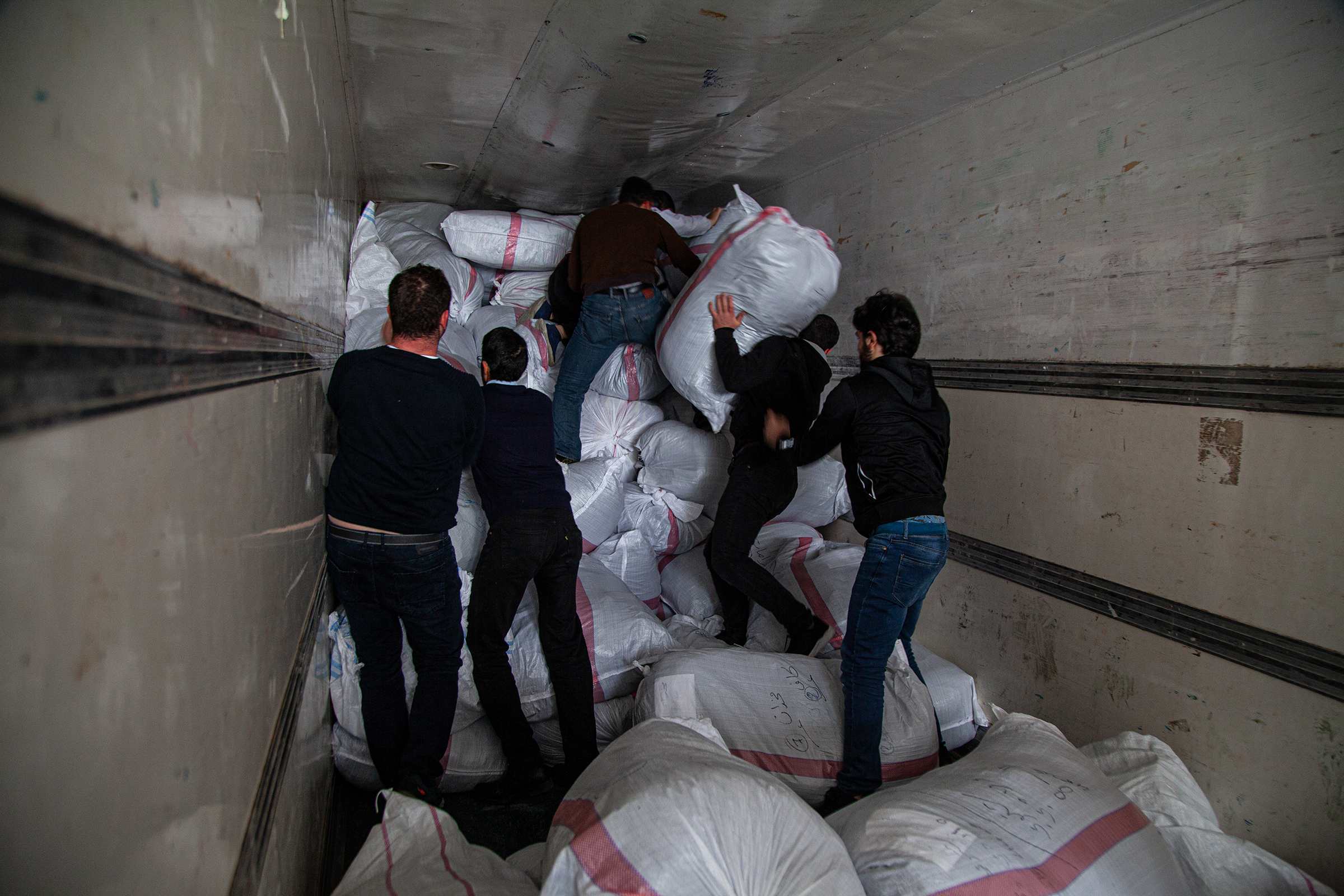 Men load sacks of humanitarian items into a truck in Gaziantep, Turkey, on Jan. 5, 2020. The aid was collected for newly displaced Syrians from Idlib. (Ahmad Al-islam—SOPA Images/Sipa USA)