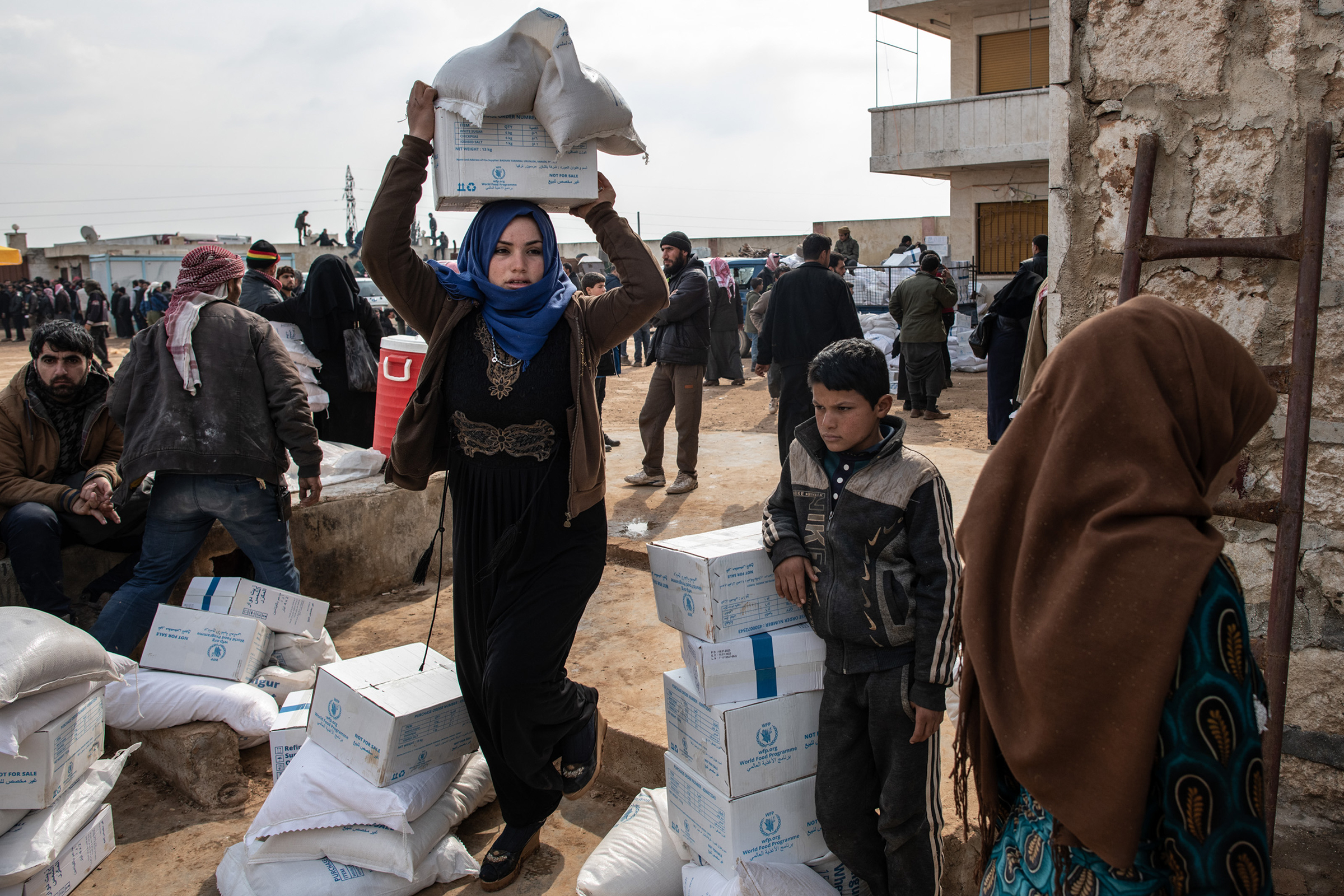A displaced woman carries a box of humanitarian aid supplied by an NGO in Idlib, Syria, on Feb. 19, 2020.
