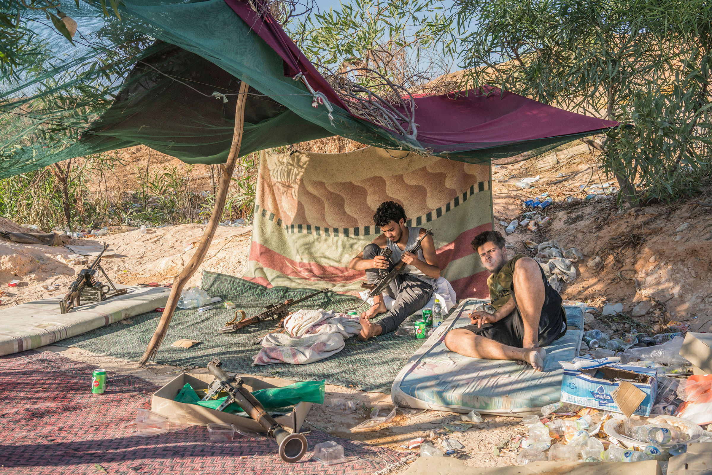 Fighters loyal to the GNA sit under a makeshift tent on the international airport front line in Tripoli on July 4, 2019. (Emanuele Satolli)