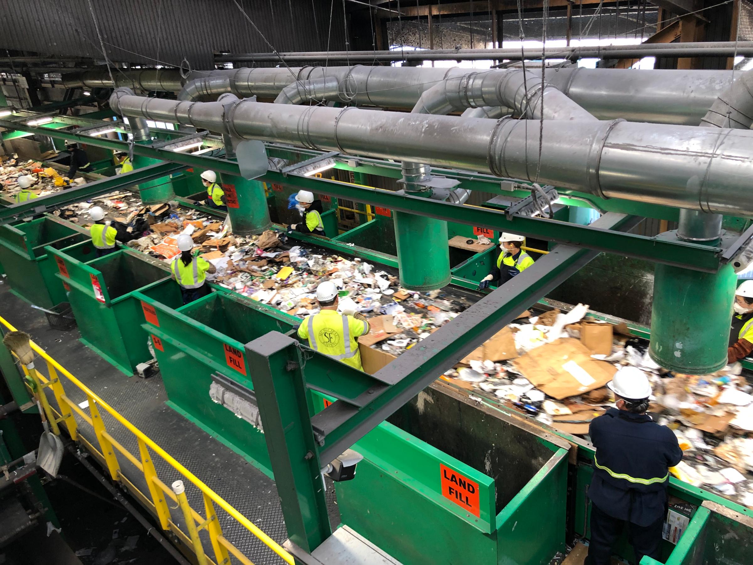 Workers sort through mixed recycling in a Recology plant in San Francisco