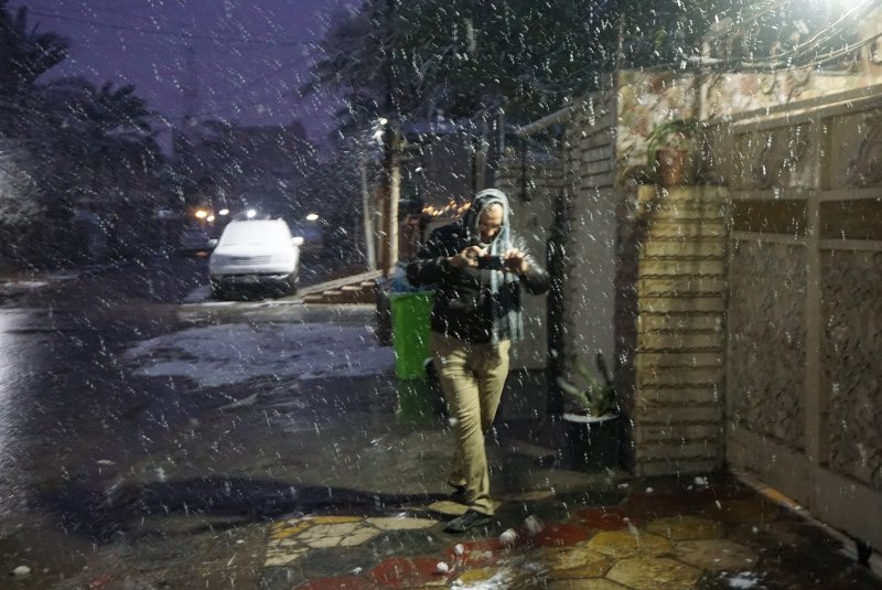 An Iraqi man takes pictures during snow fall early on Feb.11, 2020 in Baghdad, Iraq.