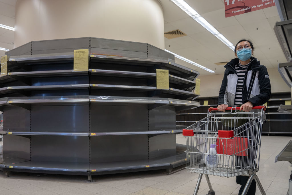 A female shopper wearing a surgical mask walks past empty
