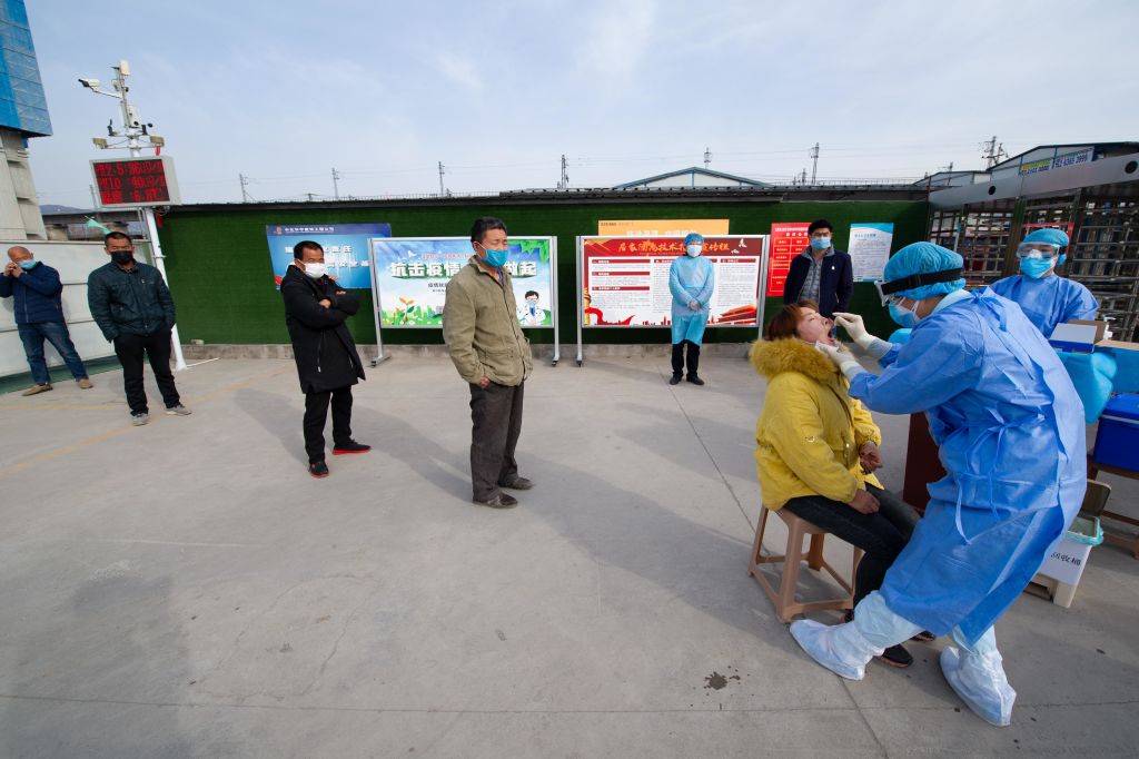 A medical worker wearing a protective suit collects sample from a migrant worker for a nucleic acid test for the COVID-19 coronavirus at a construction site amid the coronavirus outbreak on March 13, 2020 in Taiyuan, Shanxi Province of China. (Wei Liang—China News Service/Getty Images)