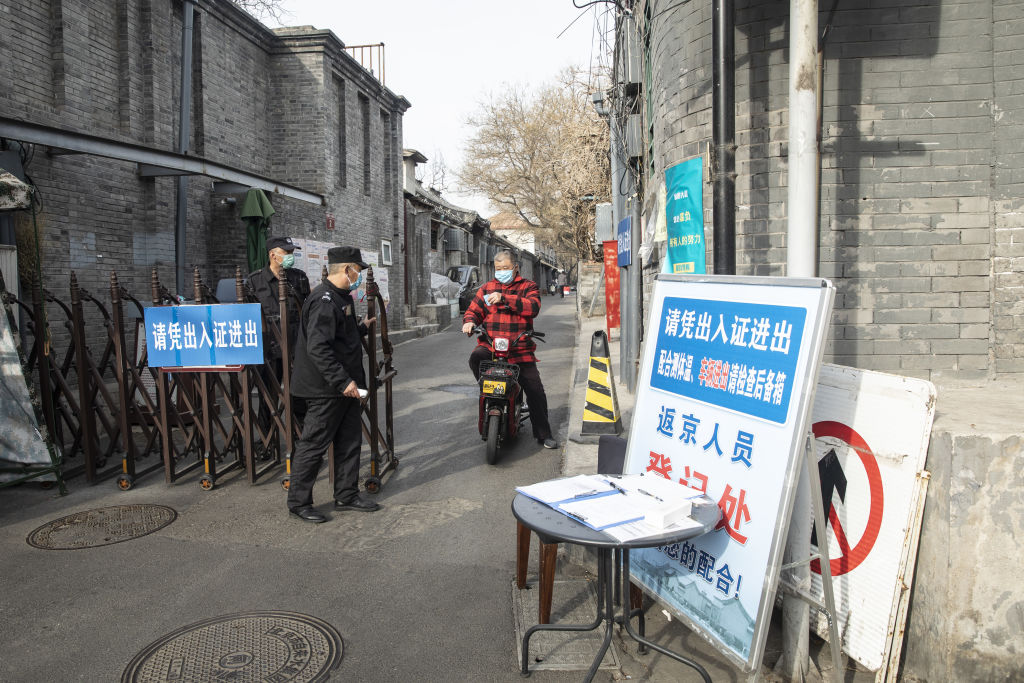 A motorcyclist wearing a protective mask shows his identification at a check point as he leaves a neighborhood in Beijing, China, on March 18, 2020. (Qilai Shen—Bloomberg via Getty Images)