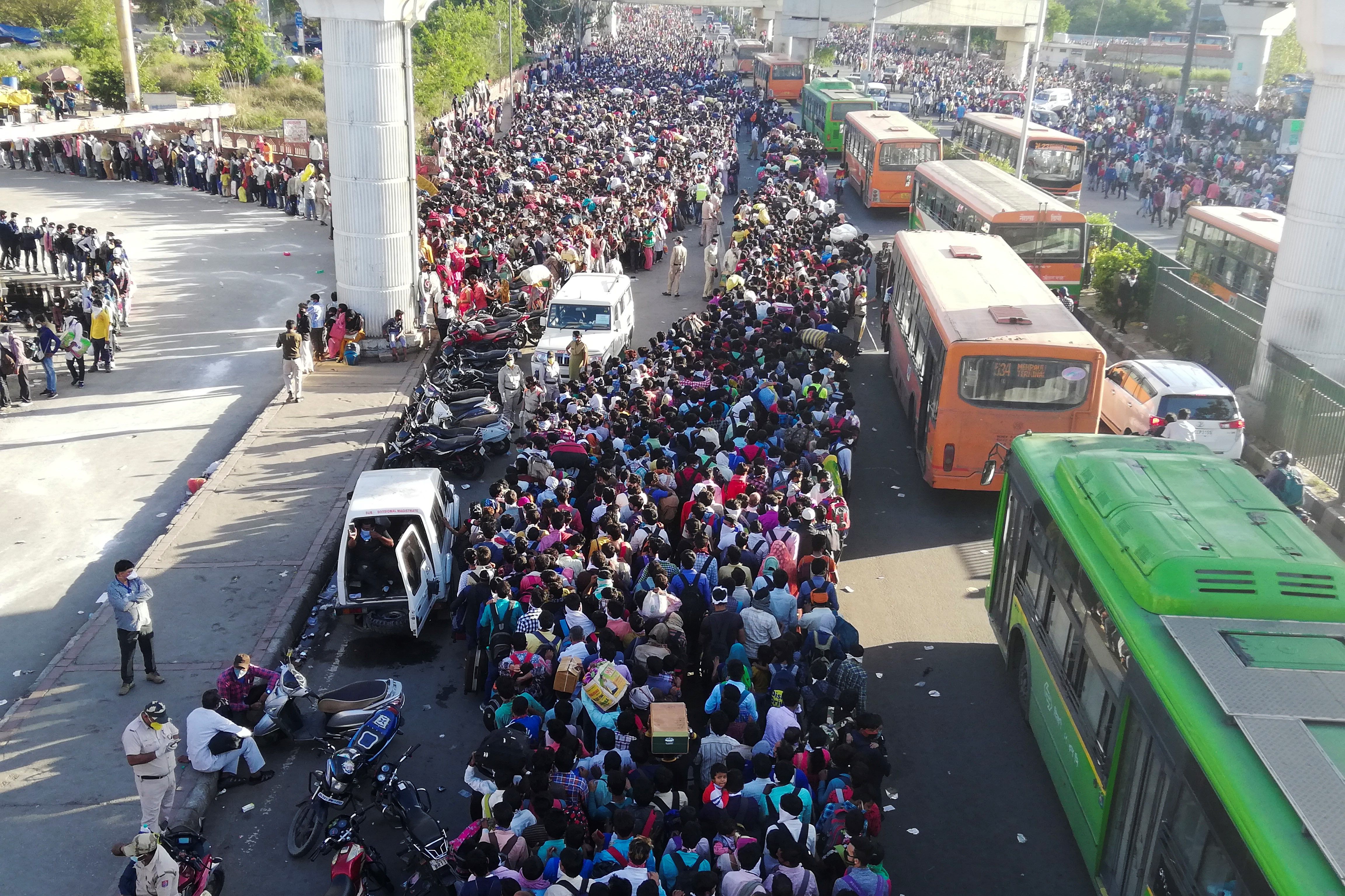 Migrant workers and their family members lineup outside the Anand Vihar bus terminal in New Delhi on March 18 to leave for their villages during a government-imposed nationwide lockdown. (Bhuvan Bagga–AFP/Getty Images)