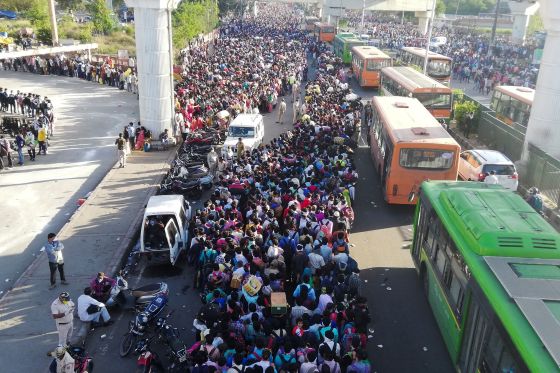 Indian migrant workers crowd to board buses to their native villages