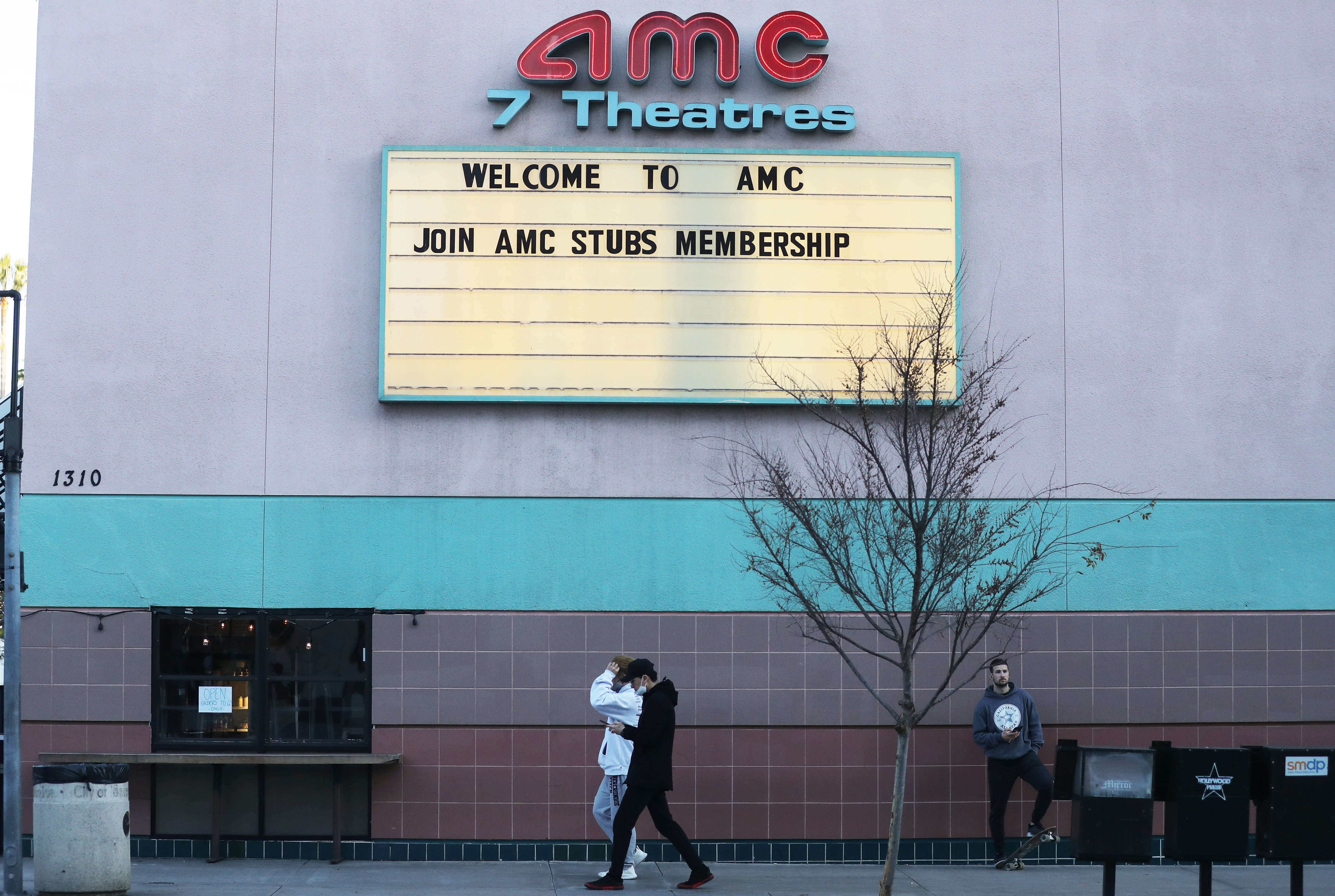 People walk outside a closed AMC movie theater on March 17, 2020 in Santa Monica, California. AMC Theatres is closing all their theaters nationwide in response to the coronavirus (COVID-19) pandemic. (Mario Tama—Getty Images)