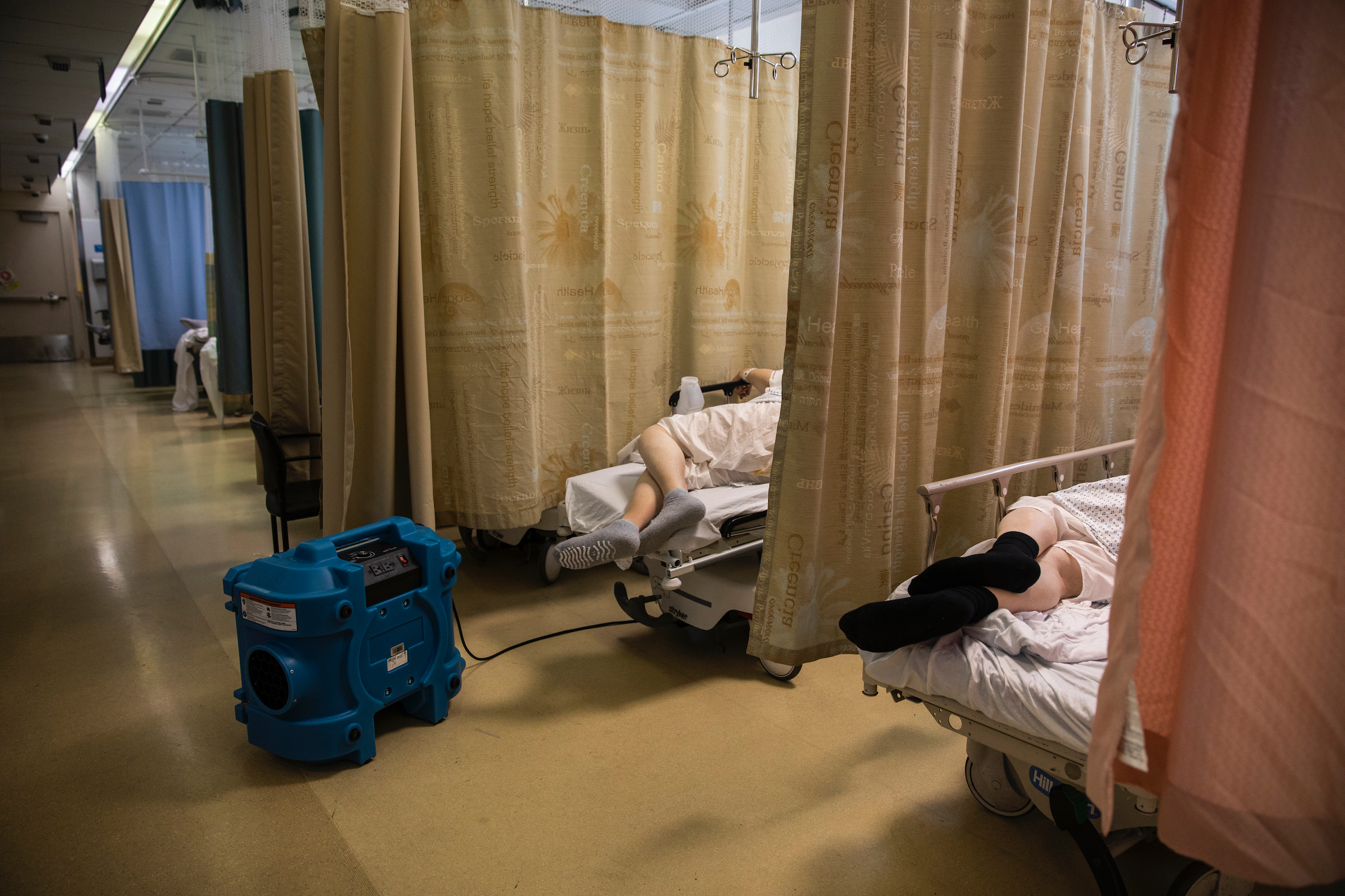 A COVID-19 patient rests with an air-purifying unit in the emergency room of Maimonides Medical Center in Brooklyn on March 26, 2020. (Benjamin Norman for TIME)