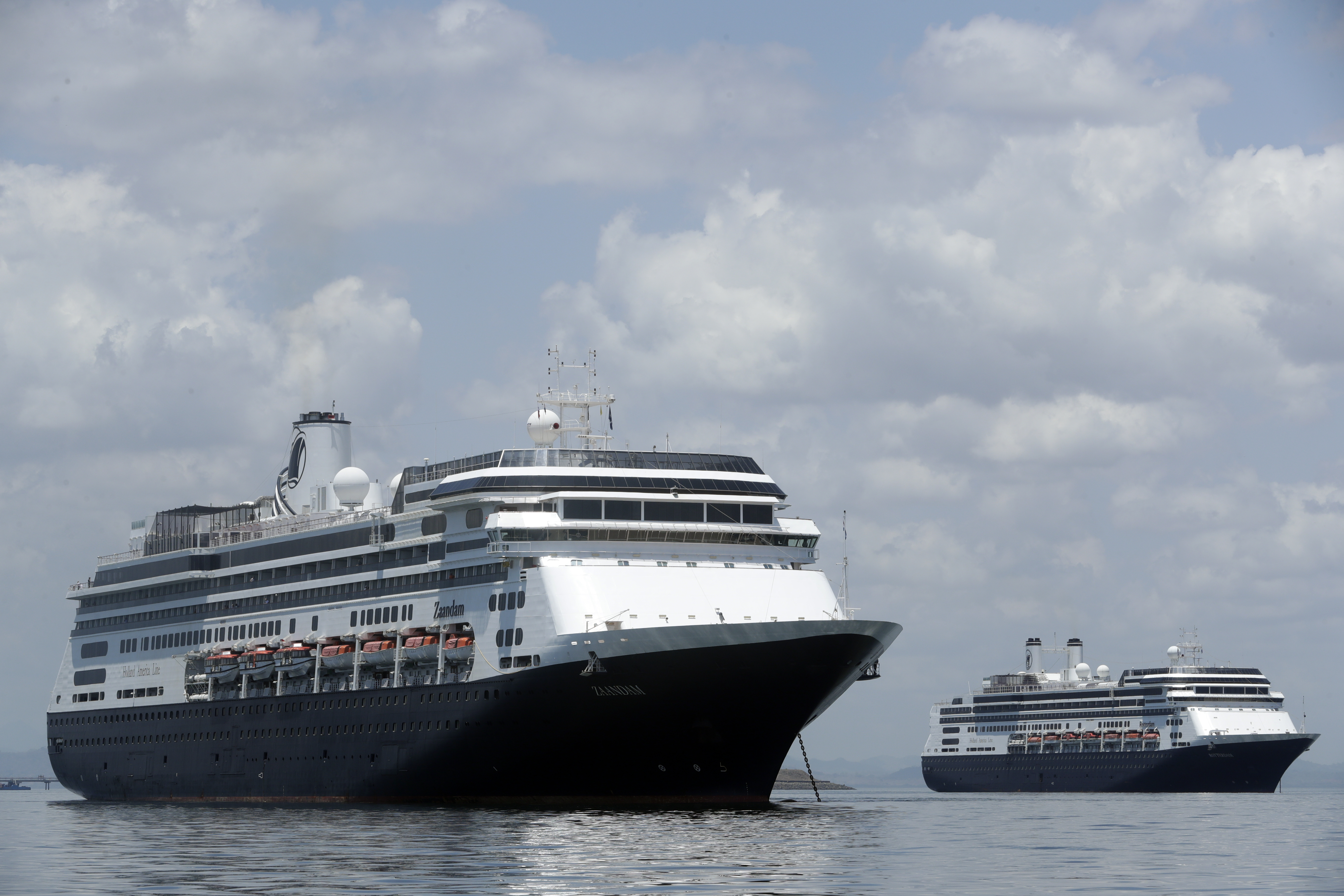 The Zaandam cruise ship, left, carrying some guests with flu-like symptoms, is anchored shortly after it arrived to the bay of Panama City, Friday, March 27, 2020, amid the worldwide spread of the new coronavirus. Health authorities are expected to board the ship to test passengers and decide whether it can cross the Panama Canal.