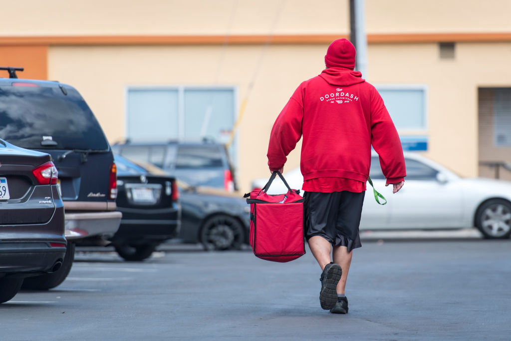A DoorDash Inc. delivery person carries an order bag outside of a DoorDash Kitchens location in Redwood City, California, U.S., on Friday, Nov. 29, 2019 (David Paul Morris—Bloomberg/Getty Images)